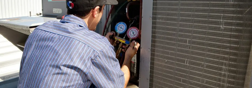 HVAC technician servicing a condenser unit in West Earl